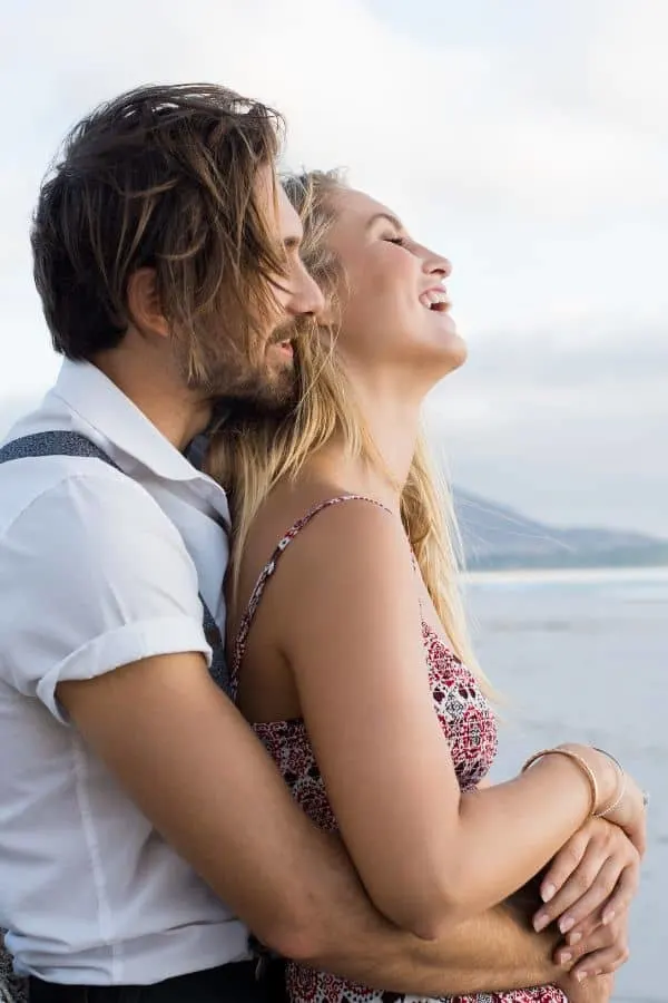 a man holding a woman while they are laughing and enjoying each other's company
