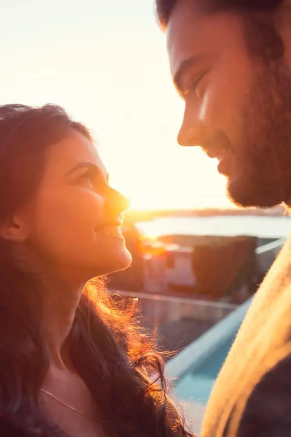 a man and a woman looking at each other's eyes with the sun glaring at the back