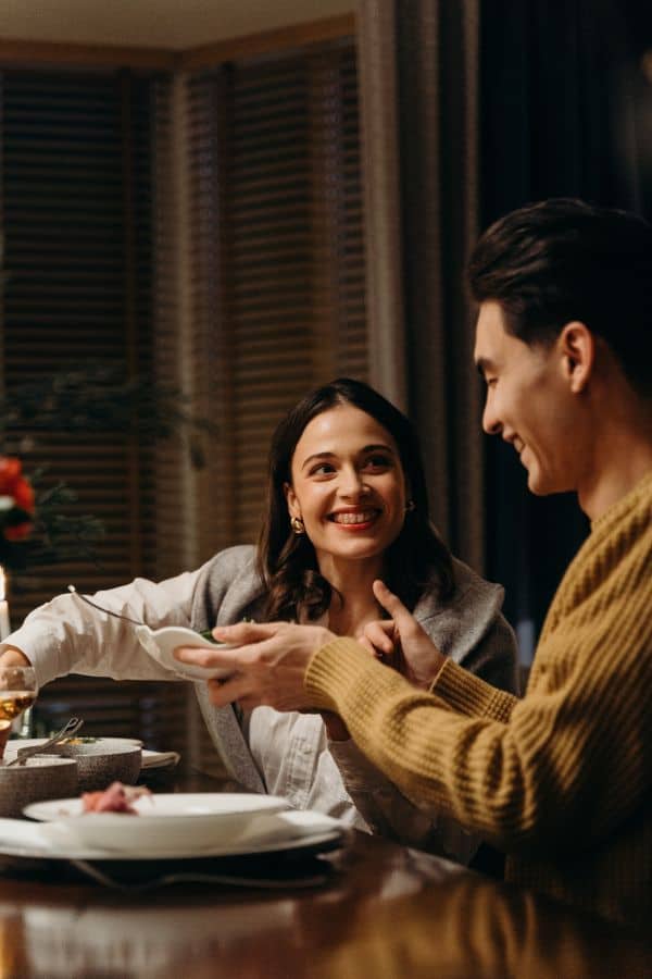 a man and a woman - a couple enjoying a dinner date while looking and smiling at each other