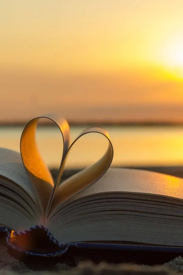 book pages shaped into a heart overlooking a sunset