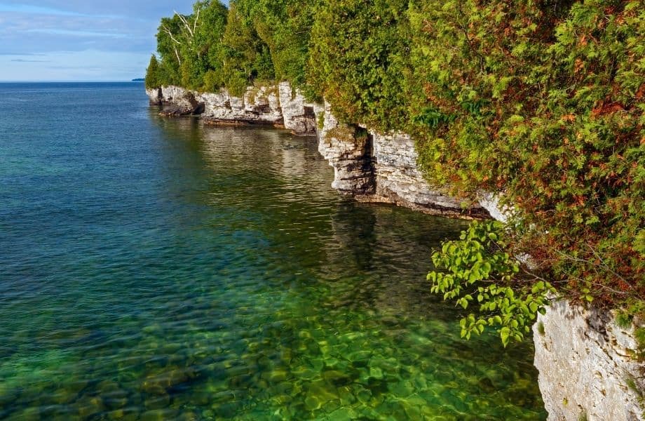 rocky cliffs along shoreline next to clear blue water