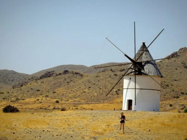 a windmill in spain with a travel blogger in front