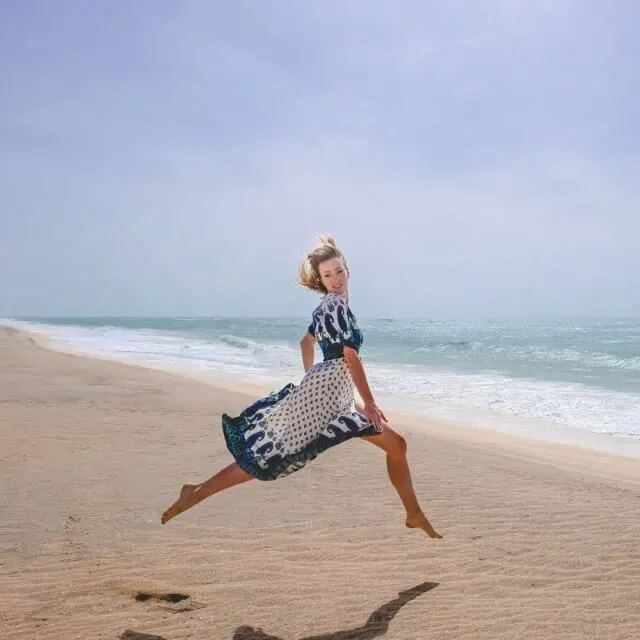 a travel blogger jumping on the beach, paulina-beach-travel-blogger