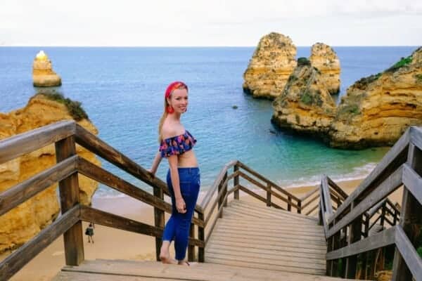 Winter in Algarve, walking down wooden stairs towards beach with rock formations