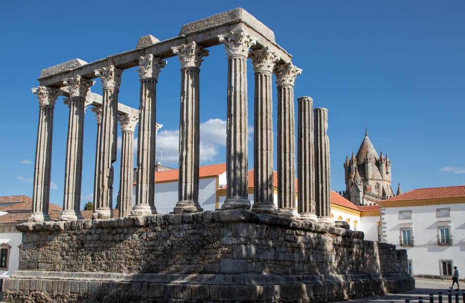 best day trips from Lagos, Portugal, elevated structure with roman column ruins next to modern white buildings with terracotta rooftops and a medieval church in background