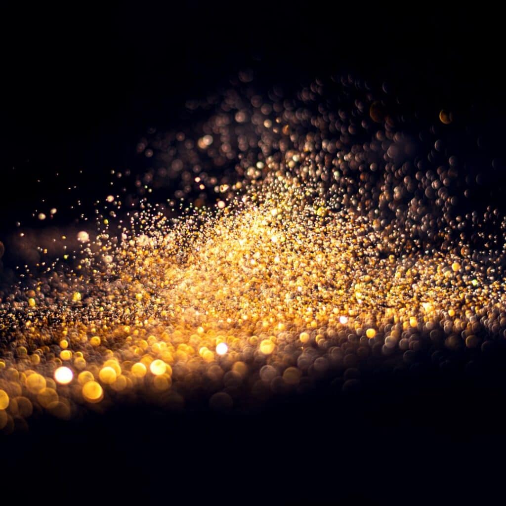 gold glitter dust on black background with bokeh effect