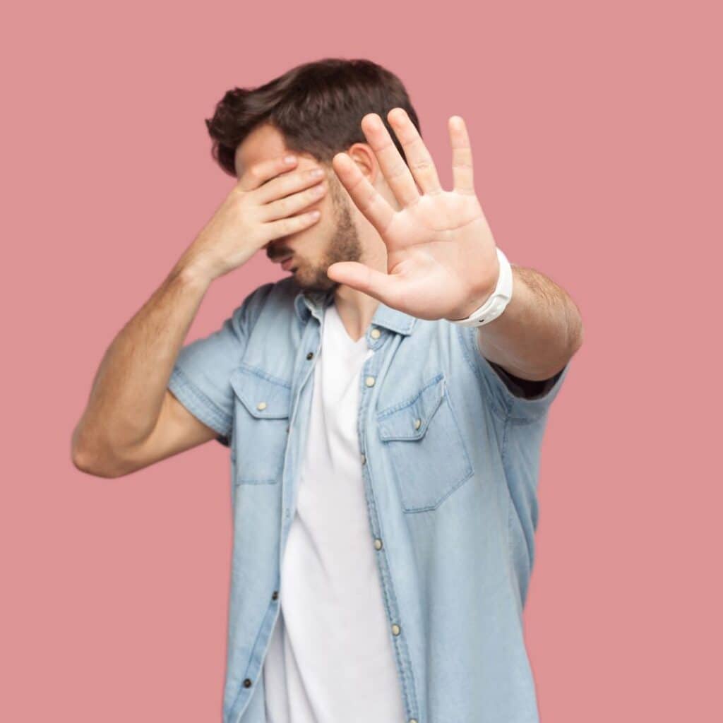 a person covering their face with their hands on a pink background