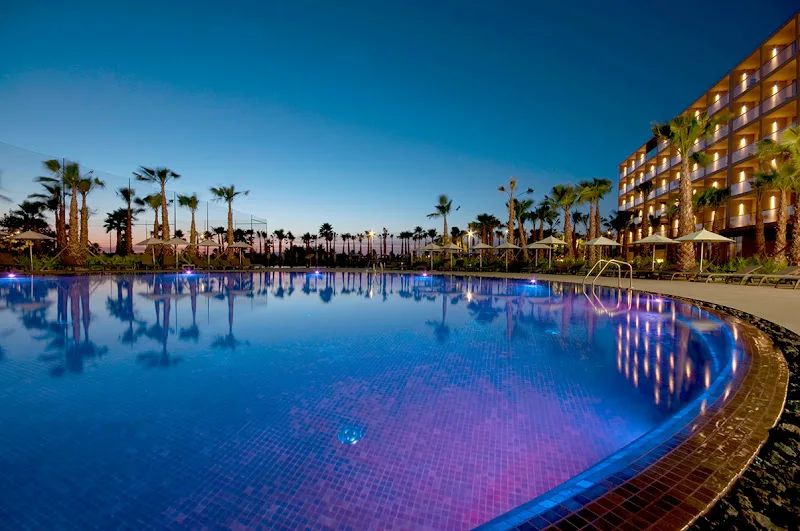 beach hotels in Albufeira, view of hotel pool lit up at night and surrounded by palm trees and lit up hotel rooms
