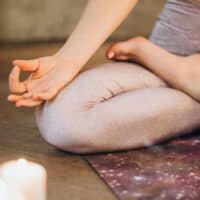 best brands for sustainable yoga leggings, person sitting in lotus position in pink leggings with candles lit nearby