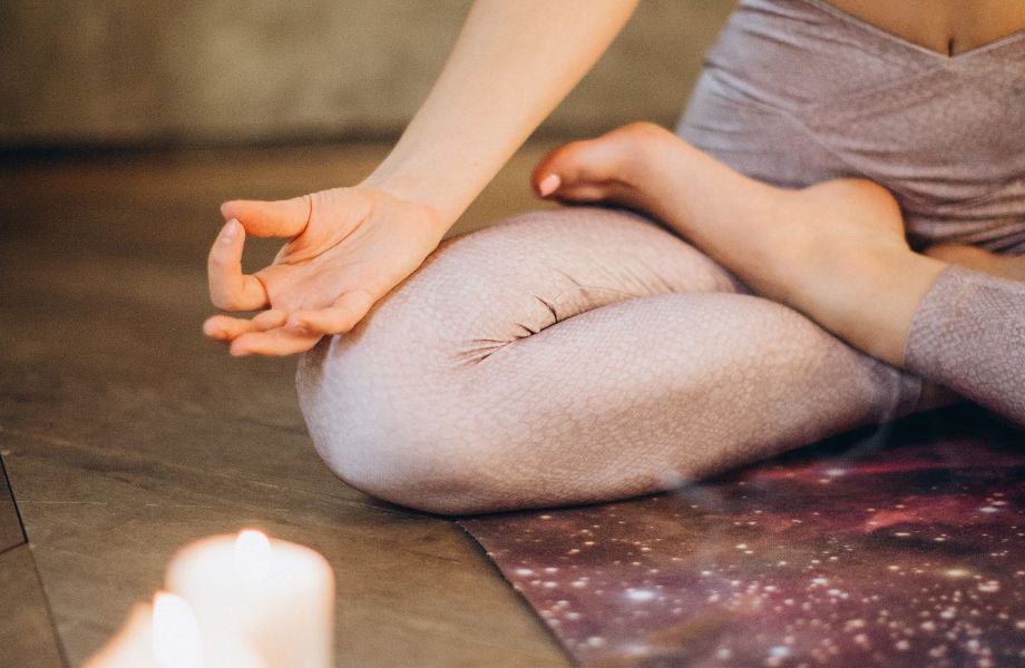 best brands for sustainable yoga leggings, person sitting in lotus position in pink leggings with candles lit nearby