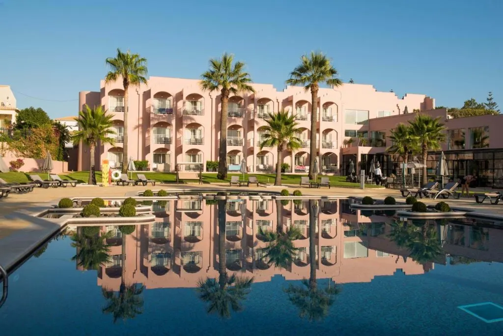 best Albufeira resorts, outside pool area in front of peach colored hotel with reflection of hotel in the pool