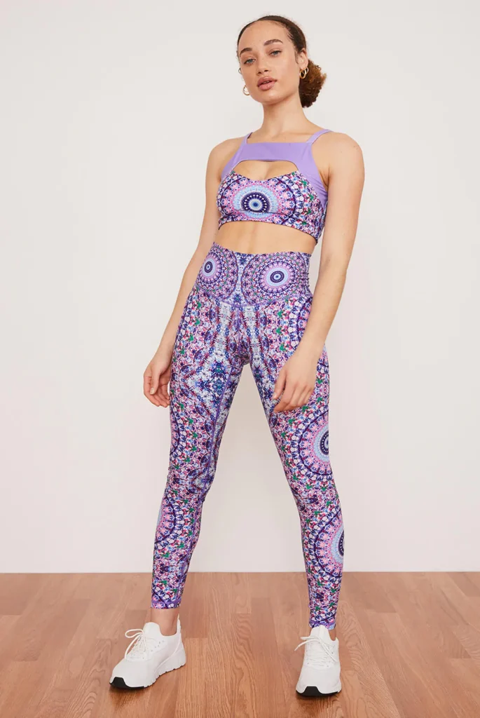 best sustainable yoga leggings, woman posing in purple yoga leggings and matching bra with intricate mandala patterns