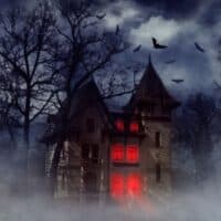Most haunted hotels in Wisconsin, spooky gothic house at night with bats flying around and windows lit up red