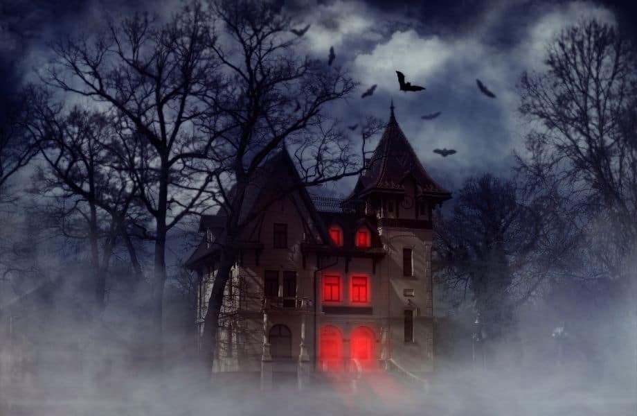 Most haunted hotels in Wisconsin, spooky gothic house at night with bats flying around and windows lit up red