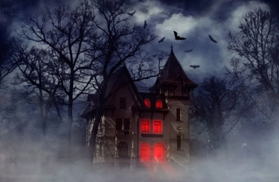 unique places to visit in wisconsin, spooky gothic house at night with bats flying around and windows lit up red