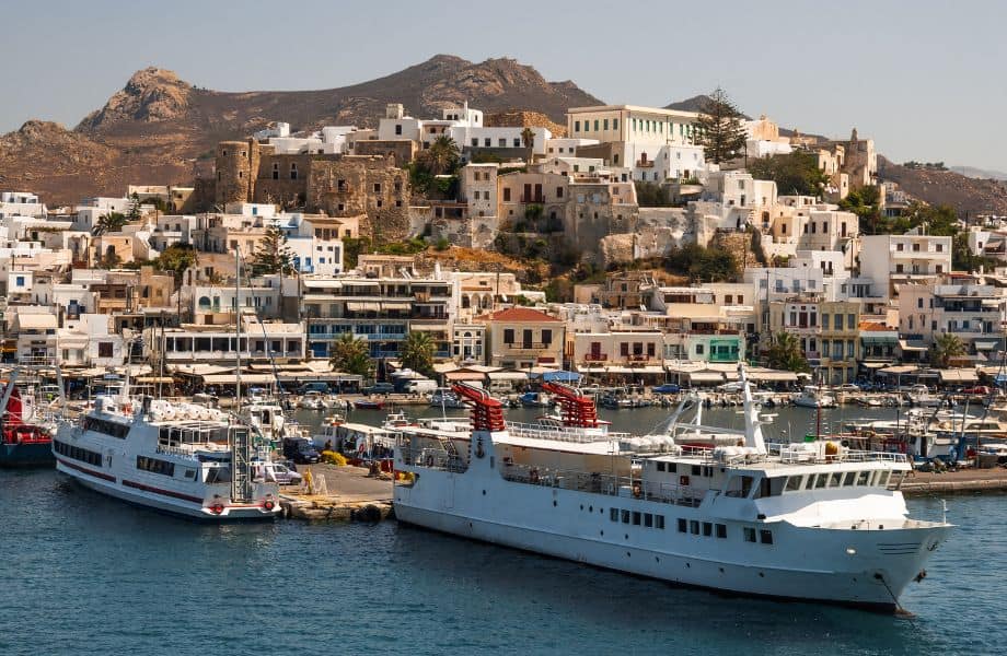 Athens to Paros ferry, ferries docking at Paros harbor surrounded by other buildings and hills in distance