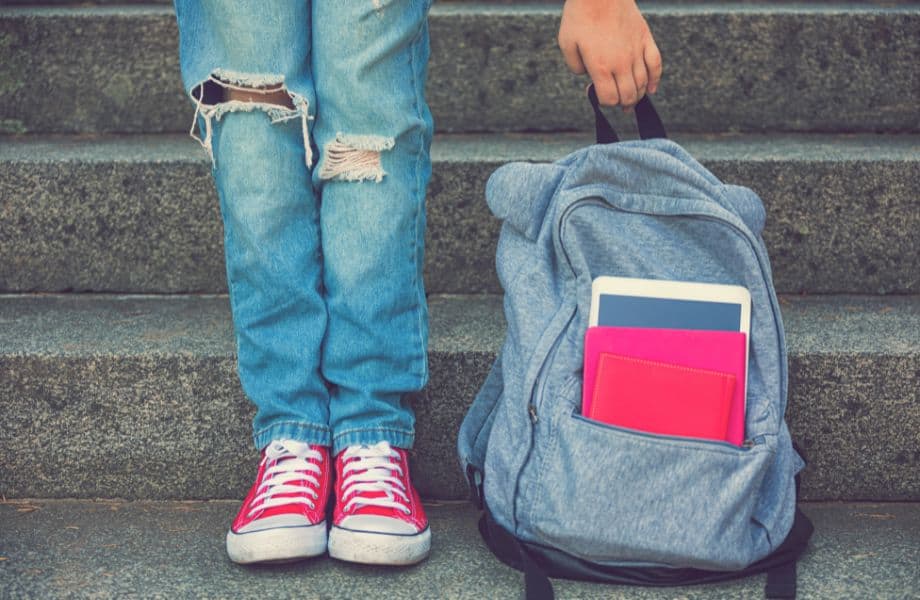 Ethical Brands for Sustainable Backpacks, person standing next to backpack on steps and leaning down to pick it up