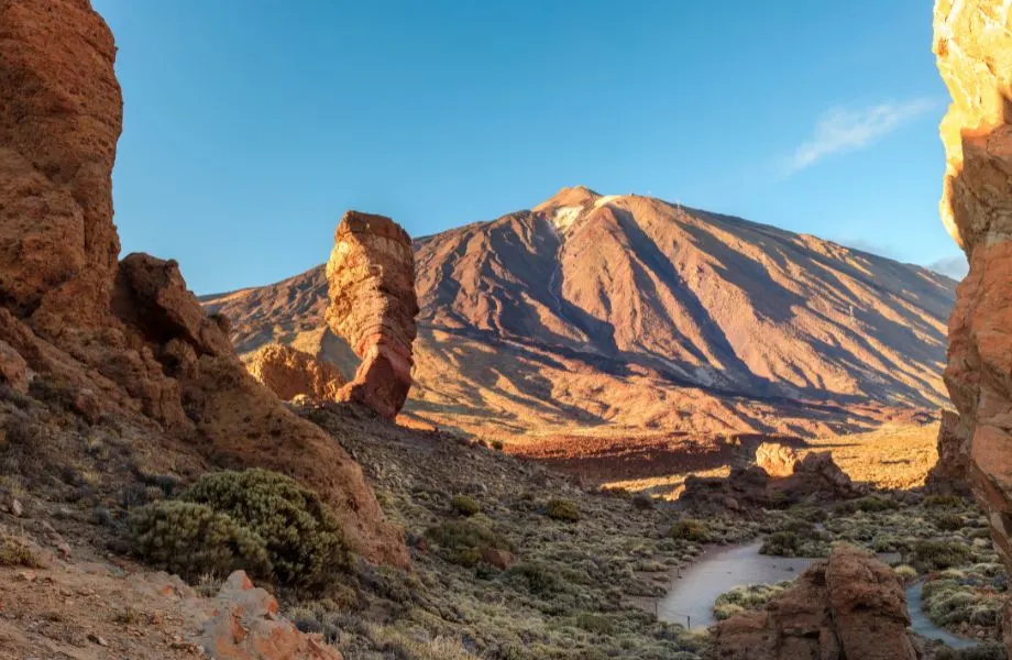 view of sun drenched mountain through canyon with path leading through the canyon