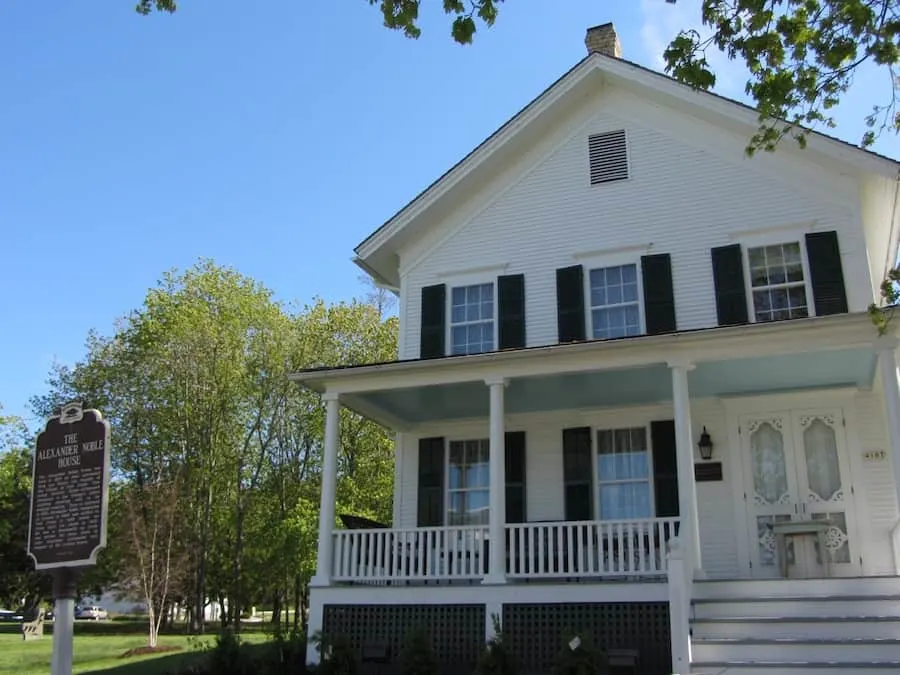 a white house with two floors by a tree