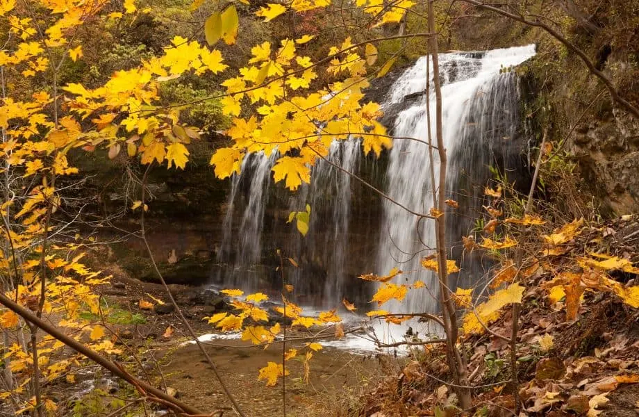best places to visit in Wisconsin in the fall, large waterfall with yellow leaves at forefront
