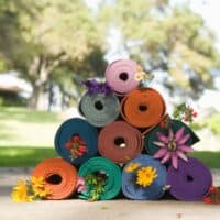 best eco-friendly yoga mats, pyramid stack of different colored yoga mats with flowers sticking out.