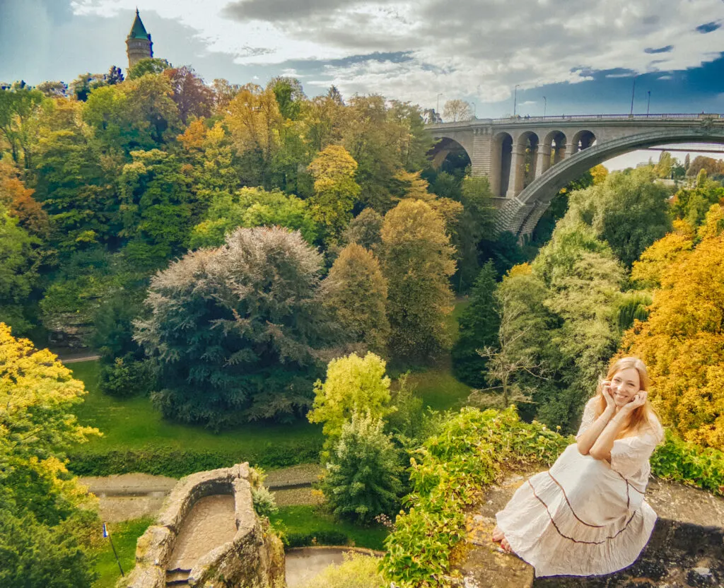 a view of a girl in luxembourg city with a view on adolphe bridge