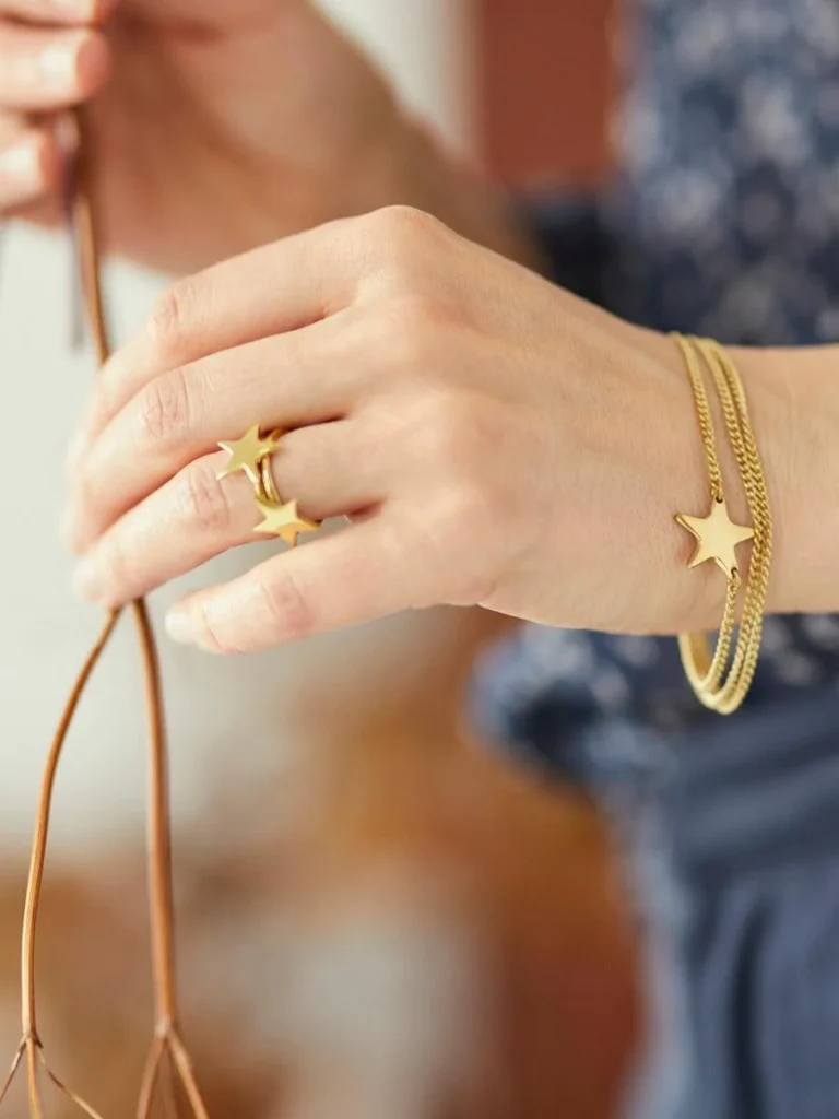 European sustainable jewelry brands, hand of person wearing matching gold bracelet and ring with stars