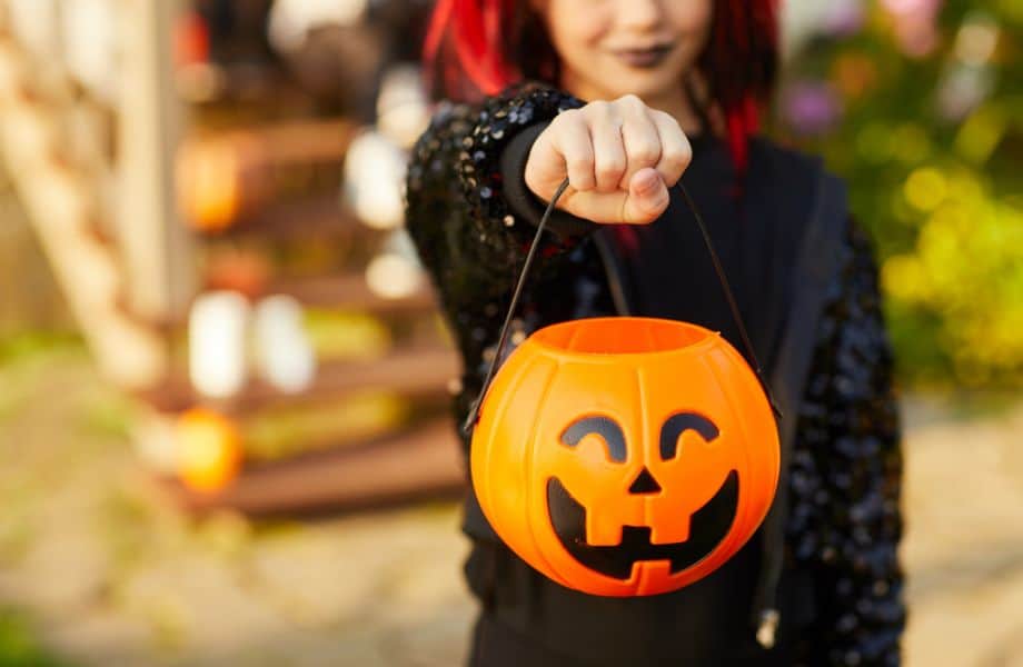 Wisconsin Halloween events, young person trick or treating and holding out pumpkin container for candy