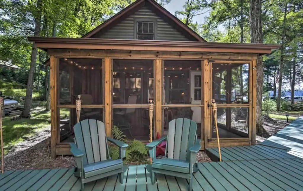 a front porch and glass front of a cabin near the woods