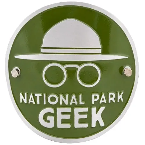 must-have national park souvenirs, green pin with outline of person in outdoorsy hat and binoculars reading national park geek