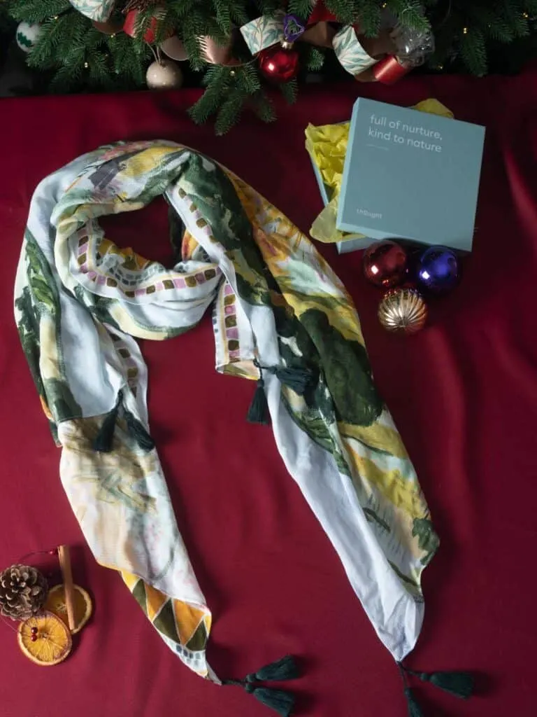 colorful sustainable xmas gifts, scarf with yellow, green and white wrapped up amongst Christmas decorations