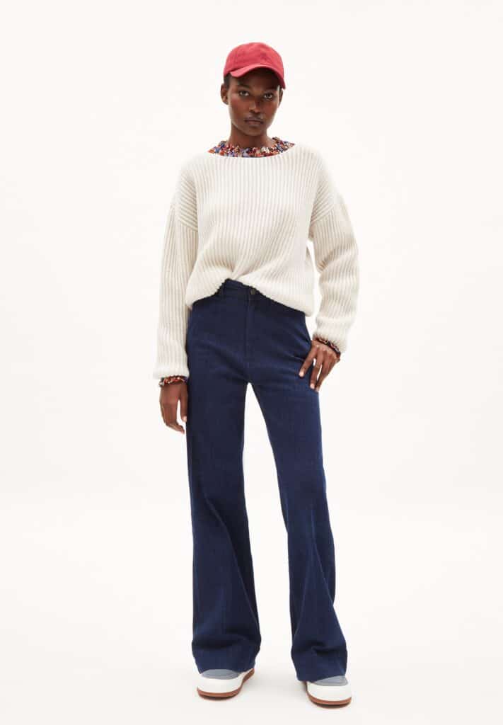 amazing zero waste brands, black woman wearing white knit sweater over dark blue jeans