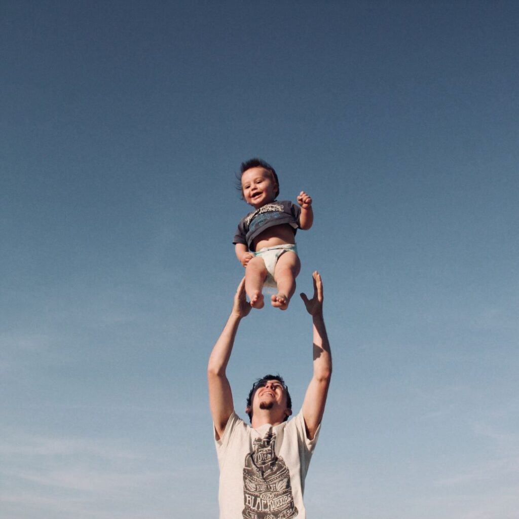 a father tossing up his son up in the air while the son is laughing