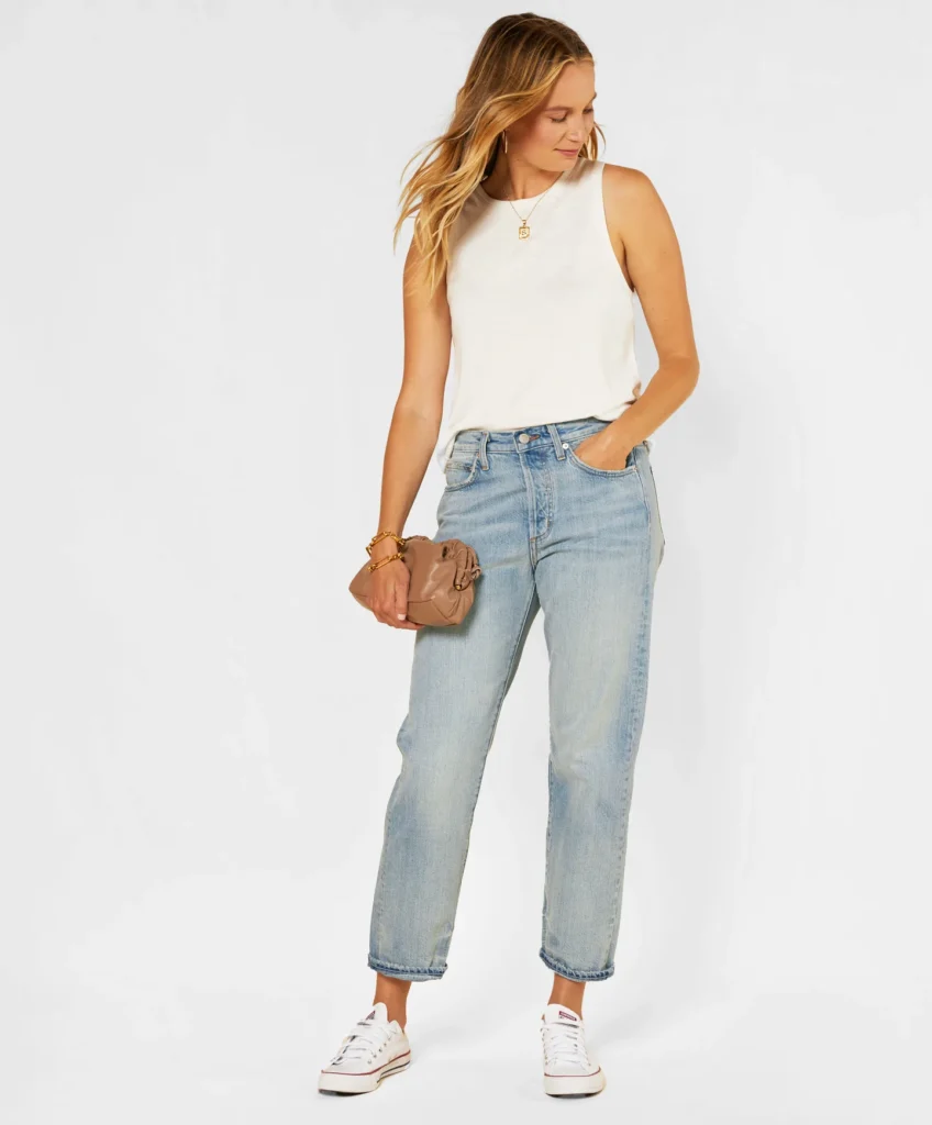 best ethical jeans brands, white woman wearing white take top and faded blue jeans