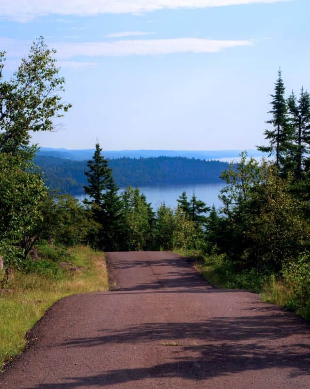 top Wisconsin road trip ideas, narrow road surrounded by trees leading down to a lake