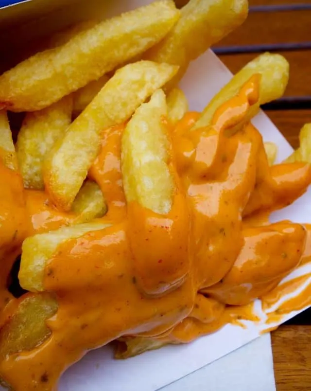 best belgium food in bruges, french fries covered with a spicy orange sauce