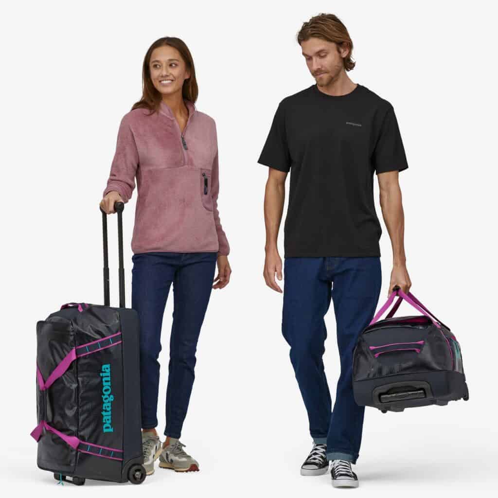 best environmentally friendly luggage, white man and woman with black duffel bags, woman's has long handle extended to pull it and man is carrying it