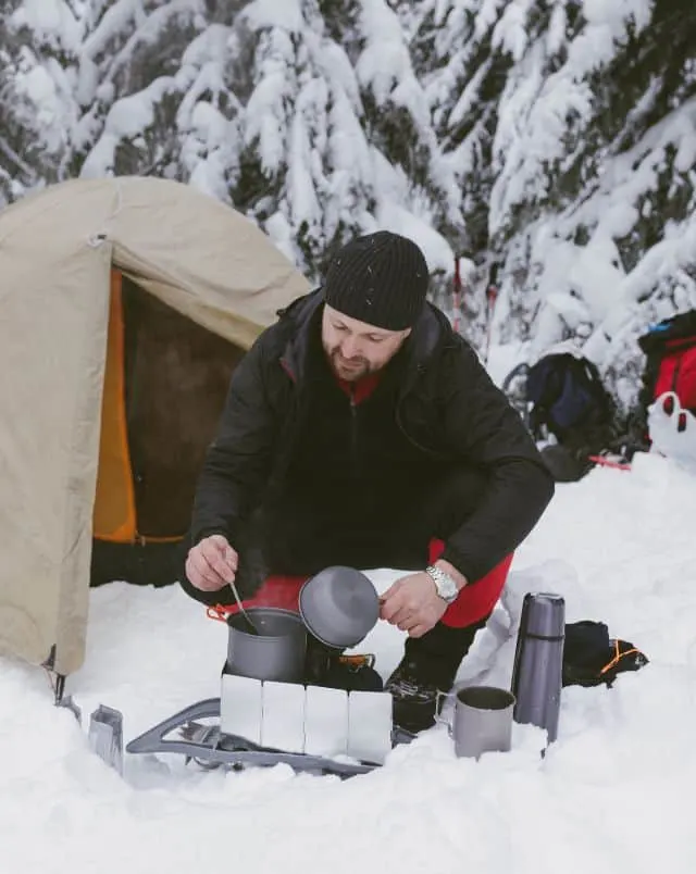 best Wisconsin camping in the winter, man cooking outside tent in the snow