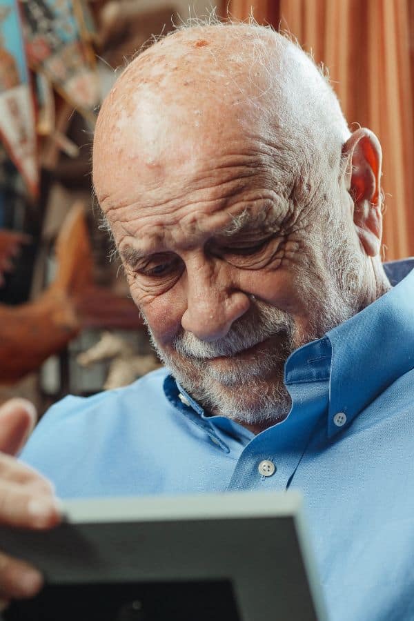 an old man with a scrunched face looking at a picture frame