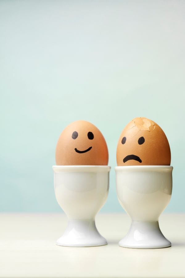 2 eggs one with a happy face, another broken with a sad face drawn