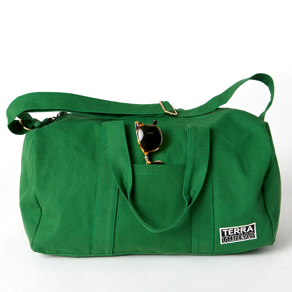 colorful eco-friendly travel bags, dark green duffel bag from Terra Thread with sunglasses sticking out of front pocket