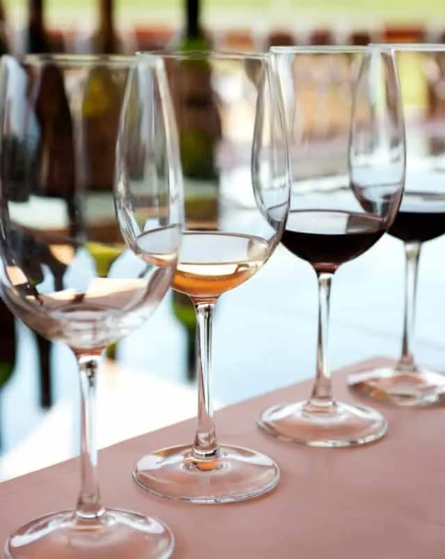 four glasses of wine lined up on a table, each glass is on slightly full and has a different wine