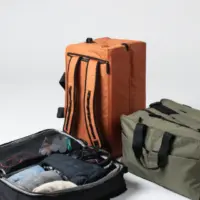 an orange backpack, a gray duffel bag and a blue bag opened with clothes inside