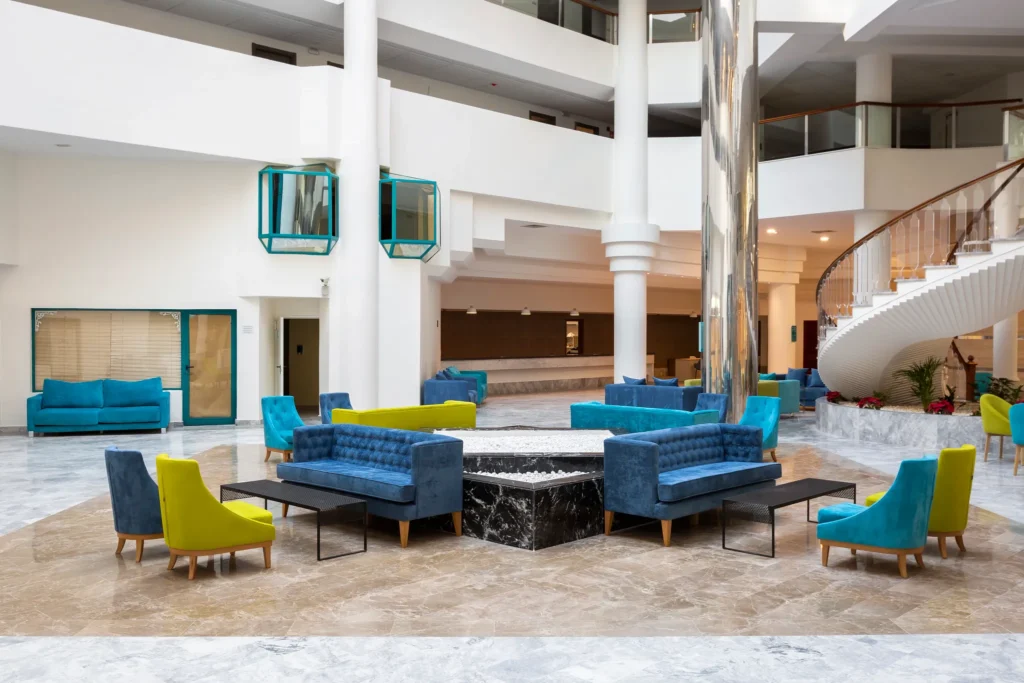 amazing mid-range hotels in Puerto de la Cruz Tenerife, Large hotel foyer with blue and yellow modern sofas and chairs surrounded by tall white painted walls and columns with a winding staircase to one side