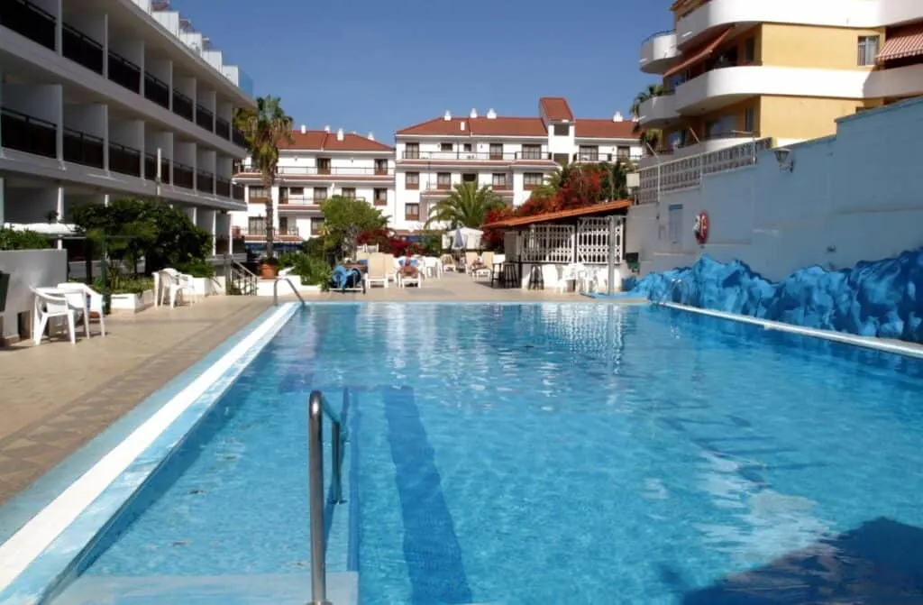 best hotels Puerto de la Cruz Tenerife offers, outdoor pool surrounded by a long hotel and in distance an outdoor seating area
