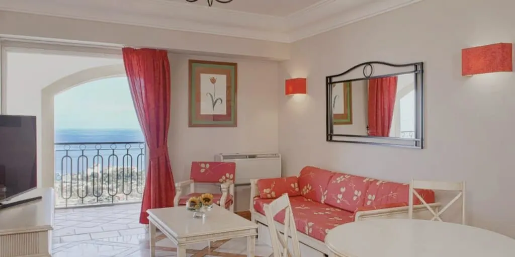 top luxury Puerto de la Cruz hotels, Lounge area of hotel suite with white and pink motif represented in the long sofa, curtains and light fixture coverings with view of the sea visible from the balcony