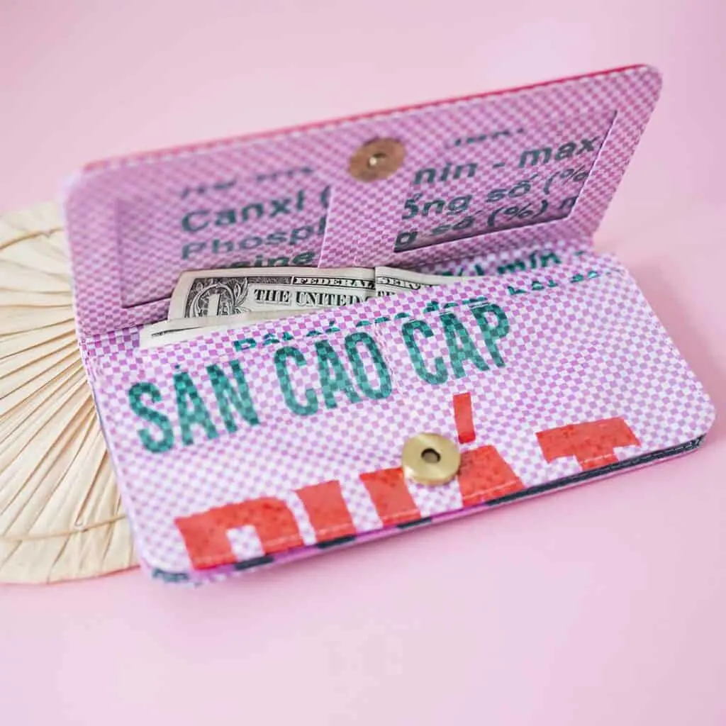 best recycled wallets, money sticking out of pink wallet made from recycled materials with Vietnamese writing