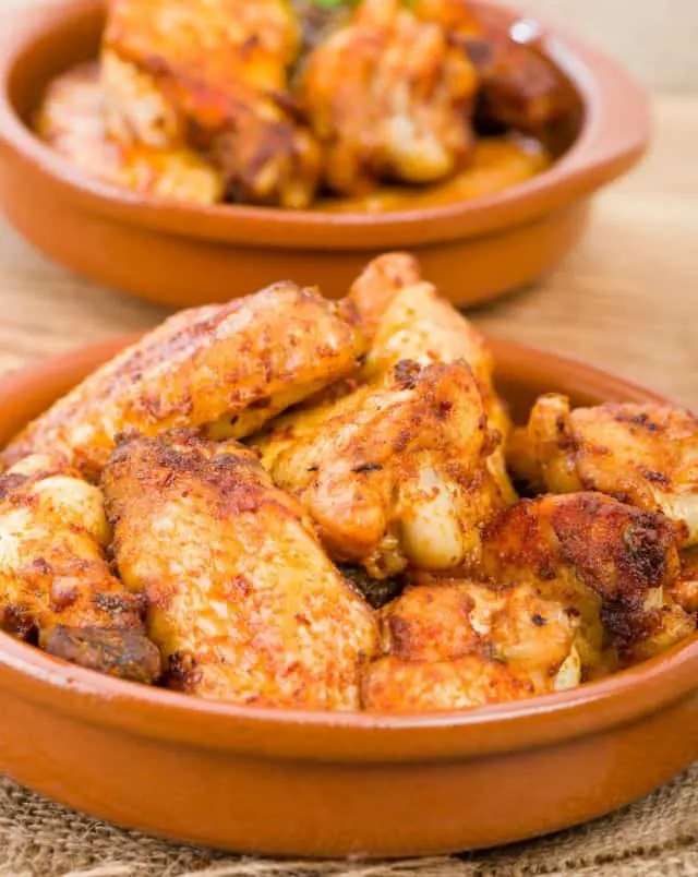 Discover the food of Spain, close up shot of Pollo al Ajillo dish in ceramic bowls