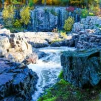 Try out some things to do in Eau Claire, waterfall running through rocky outcrops with autumnal trees behind