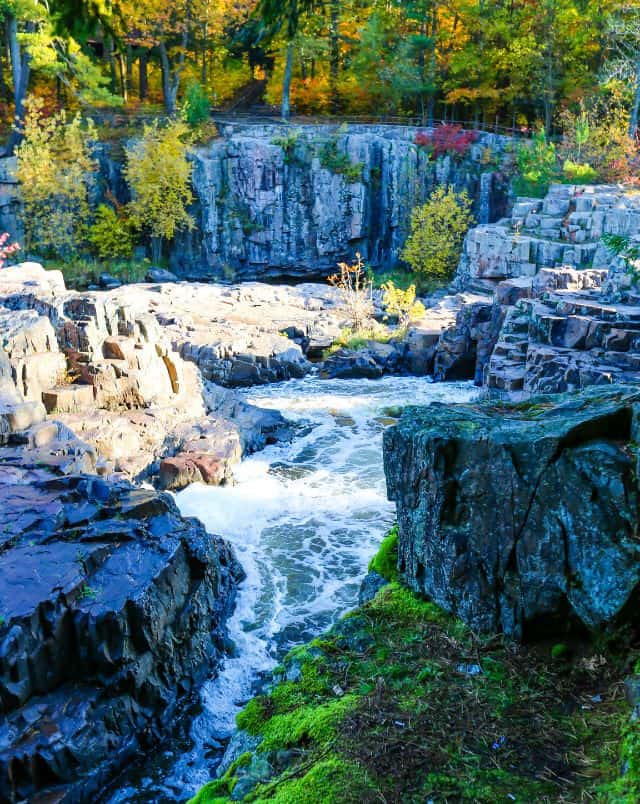 best family getaways in Wisconsin, waterfall running through rocky outcrops with autumnal trees behind